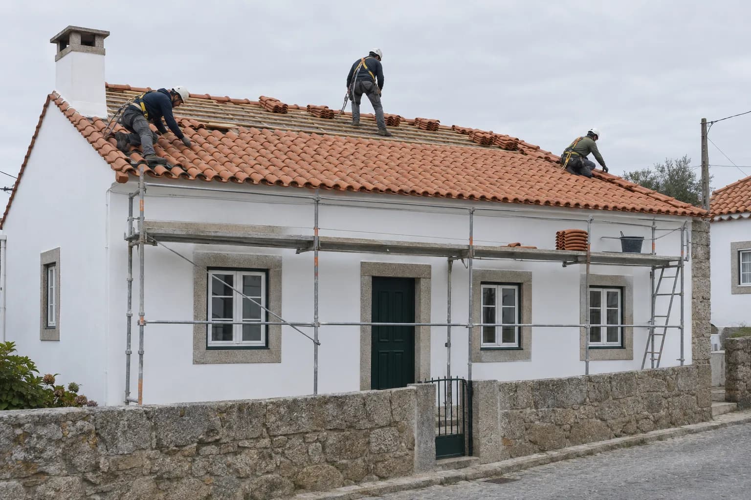 Equipa de telhadores a assentar telhas num telhado inclinado, com andaime