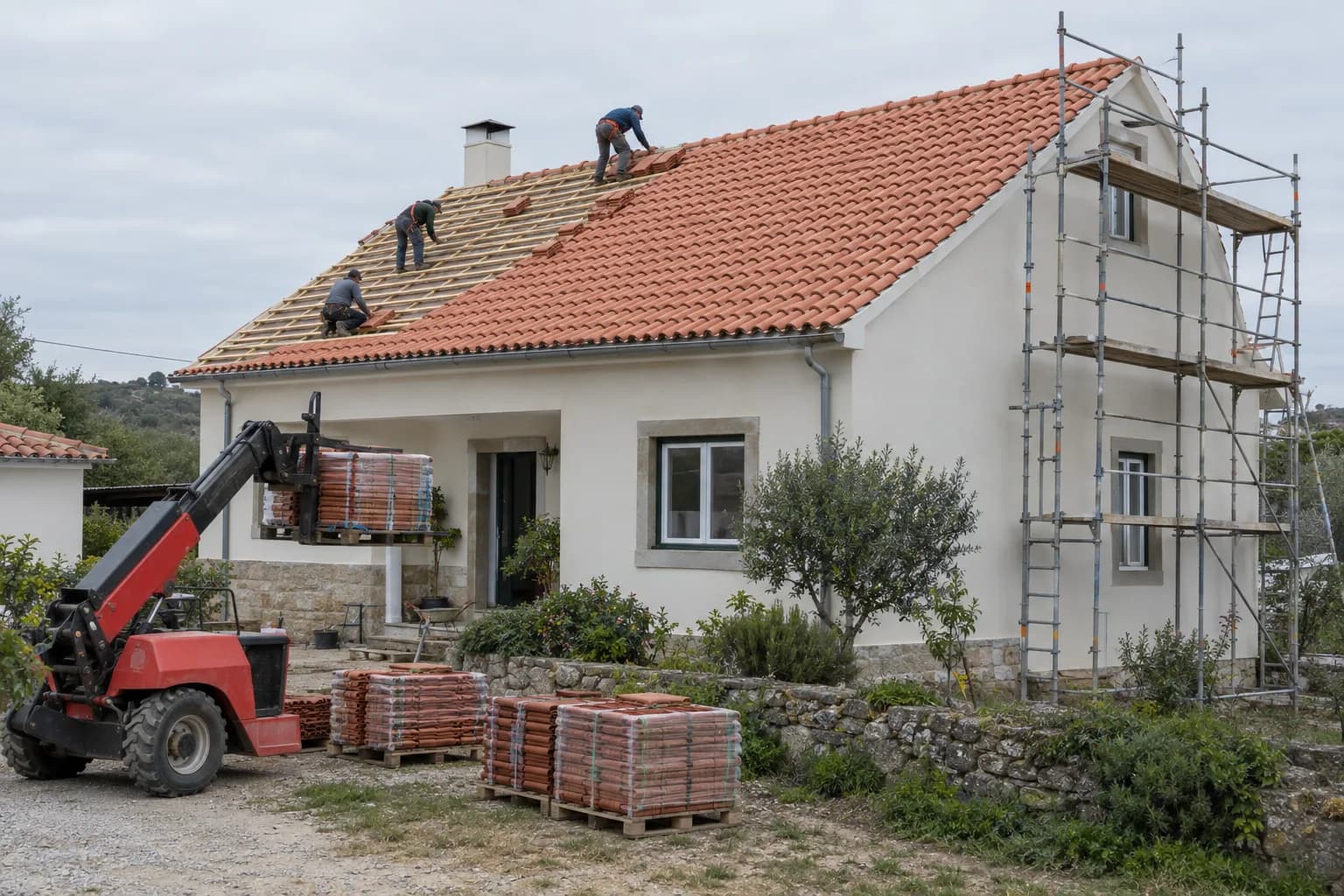 Casa rendida com o telhado em obra: ripado à vista, telha cerâmica nova, andaime na empena e paletes de telha no terreno